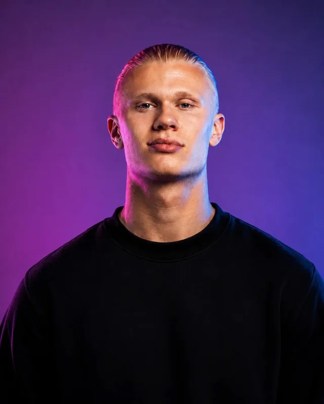A high-end photorealistic chest-up male studio portrait wearing a black crew-neck T-shirt, centered against a purple-to-deep-blue gradient with magenta and blue rim lighting.