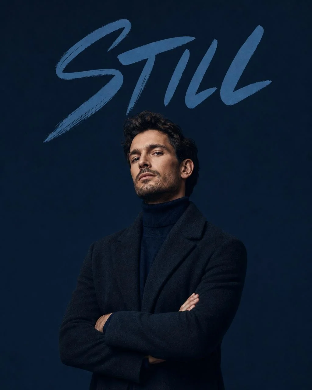 A navy monochromatic studio fashion portrait of a confident man in a dark coat and turtleneck with large brush typography reading STILL above him.
